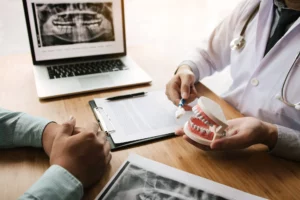 Dentist using a model and x-rays to explain treatment to a patient