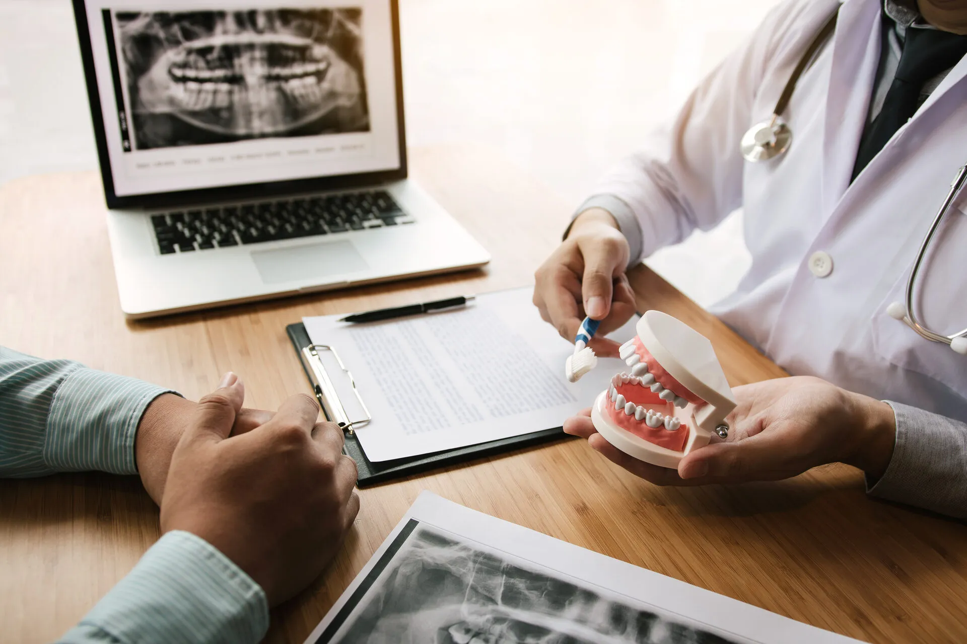 Dentist using a model and x-rays to explain treatment to a patient